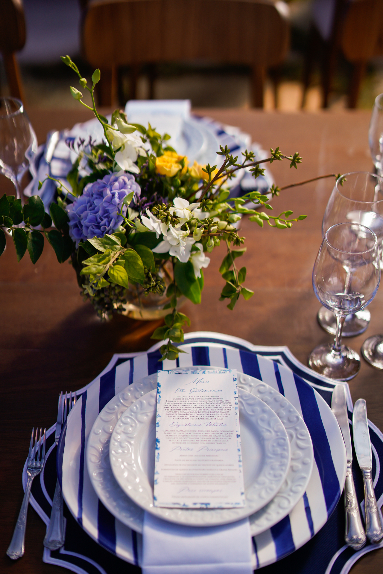 Mesa com louça azul e branca, taças e arranjo floral delicado