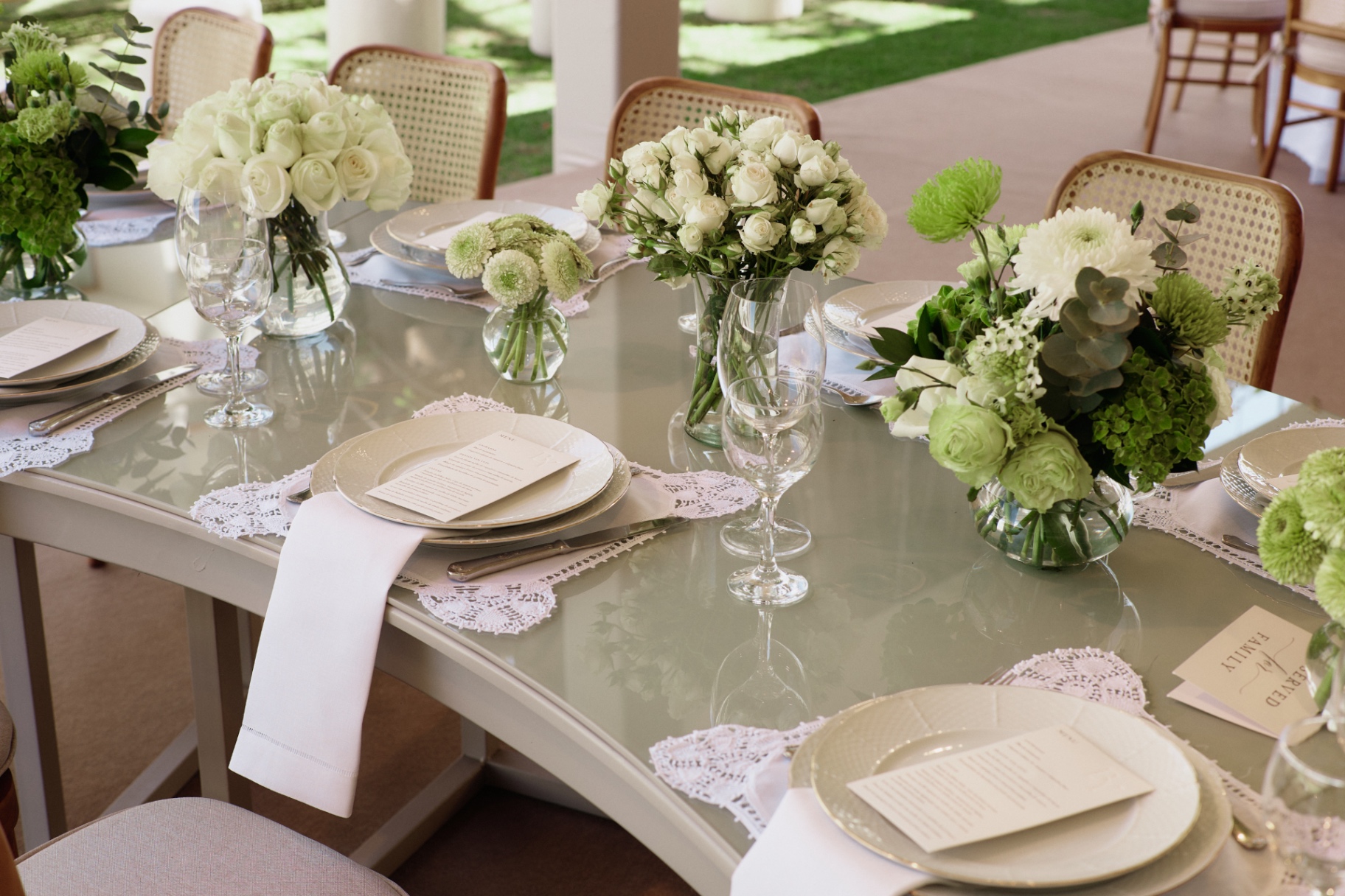 Mesa de vidro com flores brancas, taças e lugares cuidadosamente preparados