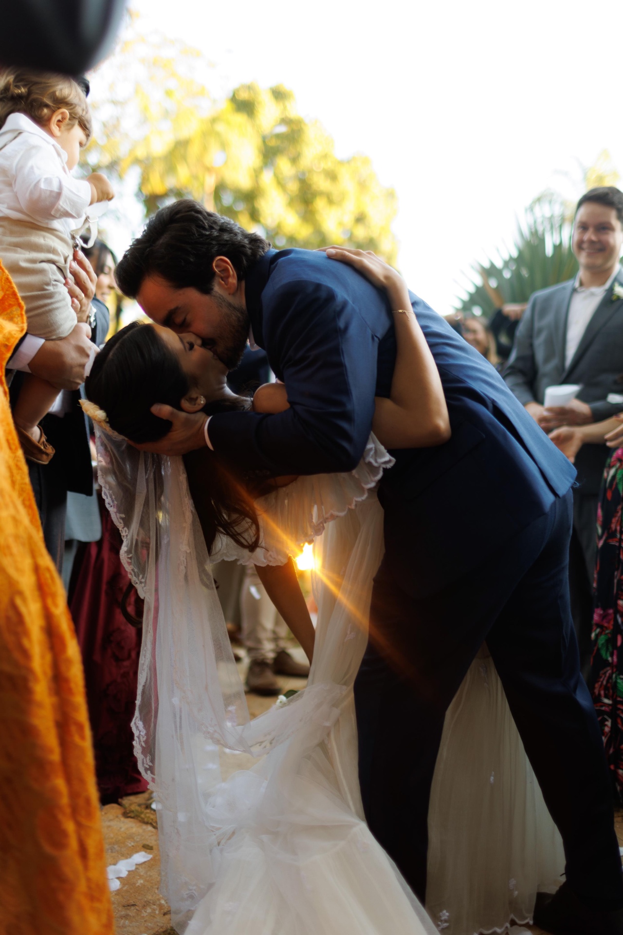Noivos se beijando ao ar livre diante dos convidados